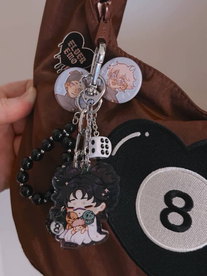 clear acrylic keychain featuring choso from jujutsu kaisen sleeping featured on a customer's brown bag with a heart-shaped 8 ball