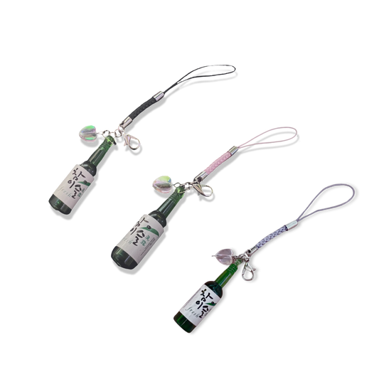 Three soju charms are lined up from left to right in three different variants: black, pink, and purple braided phone straps respectively.