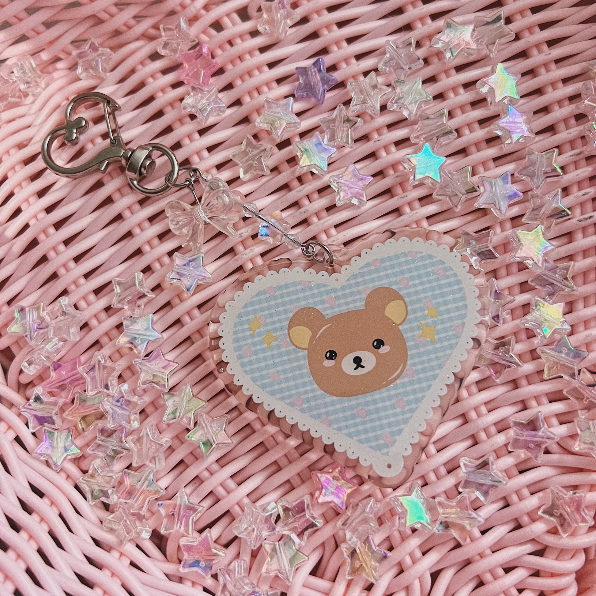 Blue bear acrylic heart charm with pink weaved basket background with holographic stars.