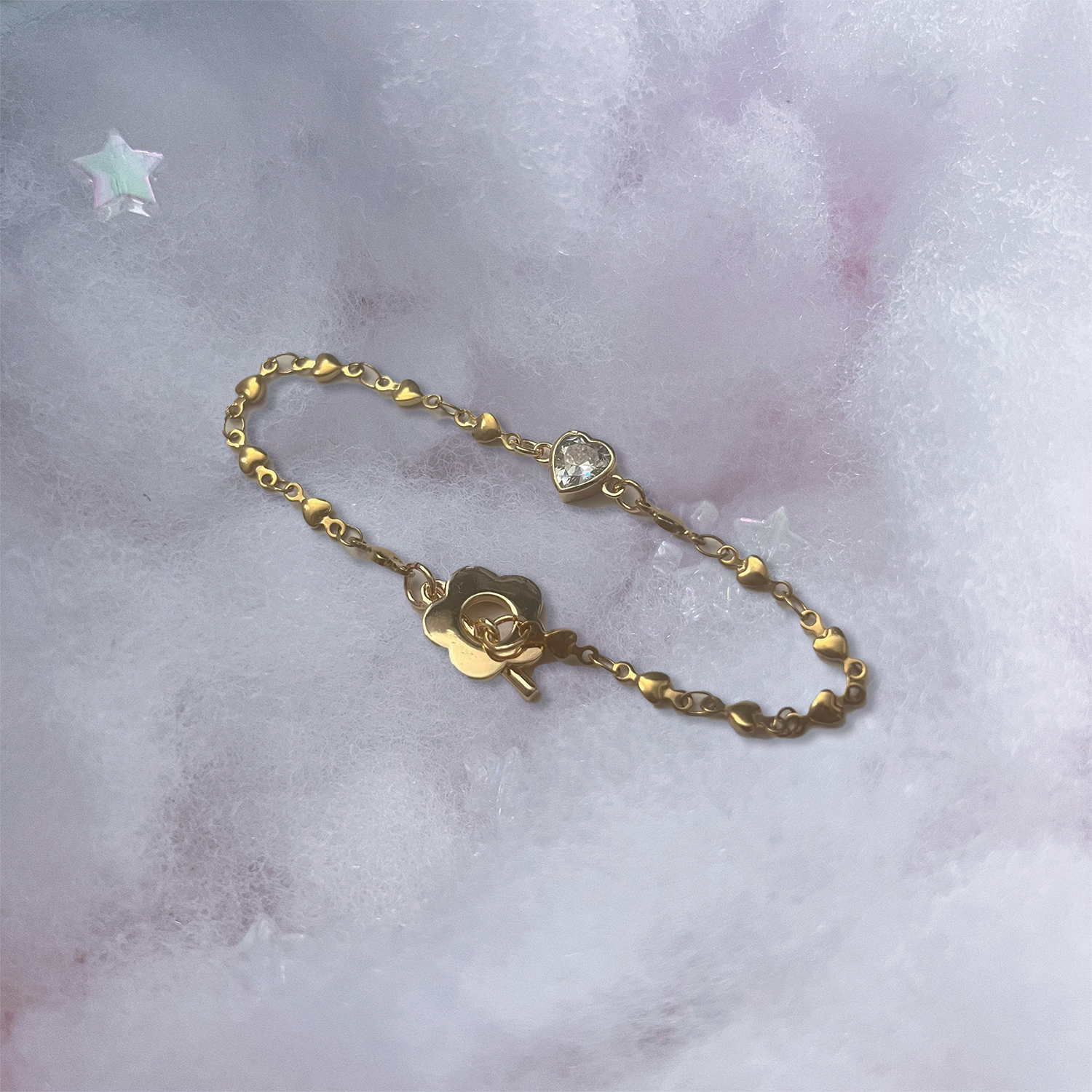 Dainty Soft Lover Bracelet in Gold neatly arranged as a product photo. Bracelet features details of gold heart links, a dainty heart crystal connecting charm, and daisy-style clasp.