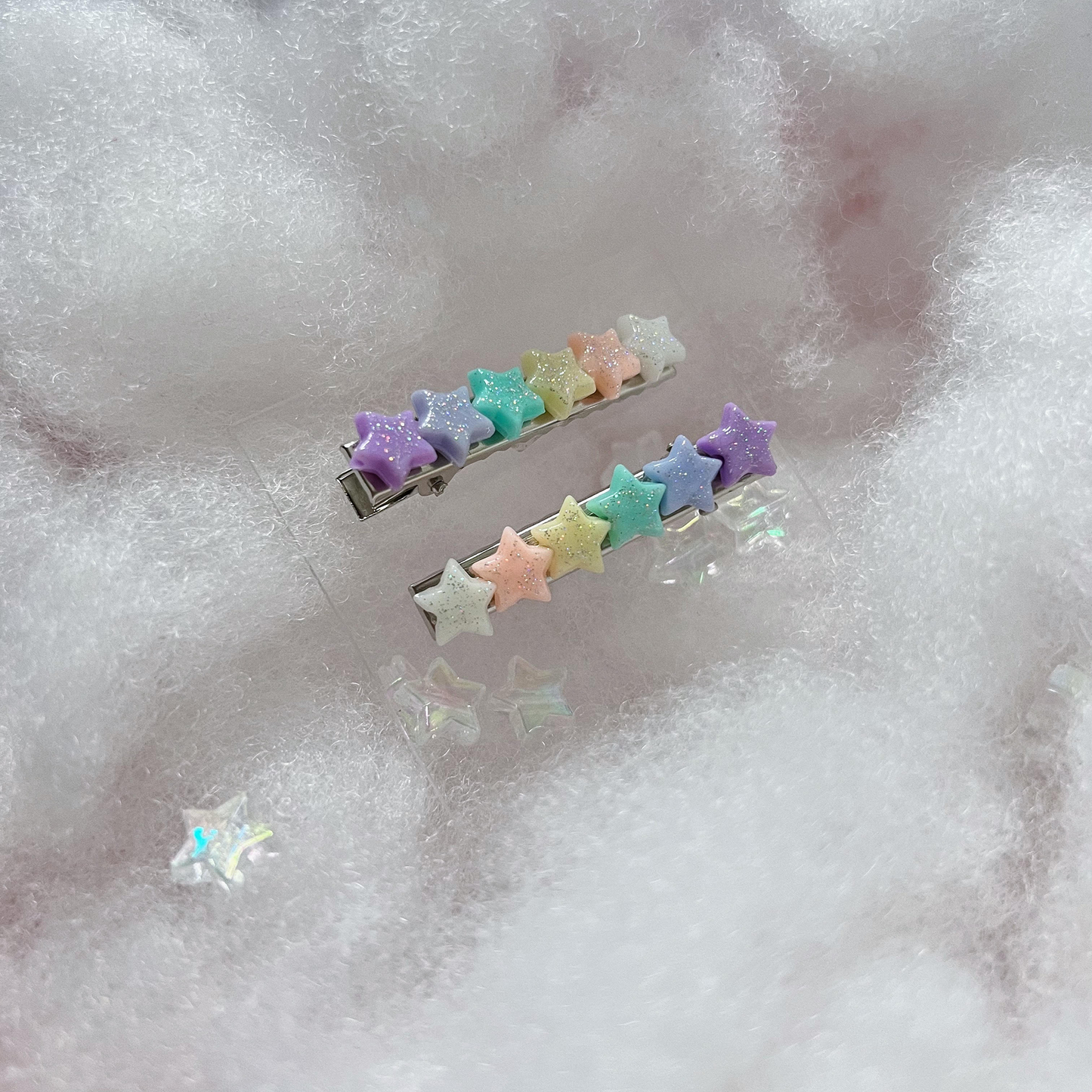 Pastel rainbow star hair clips in a dreamy white cloud background.