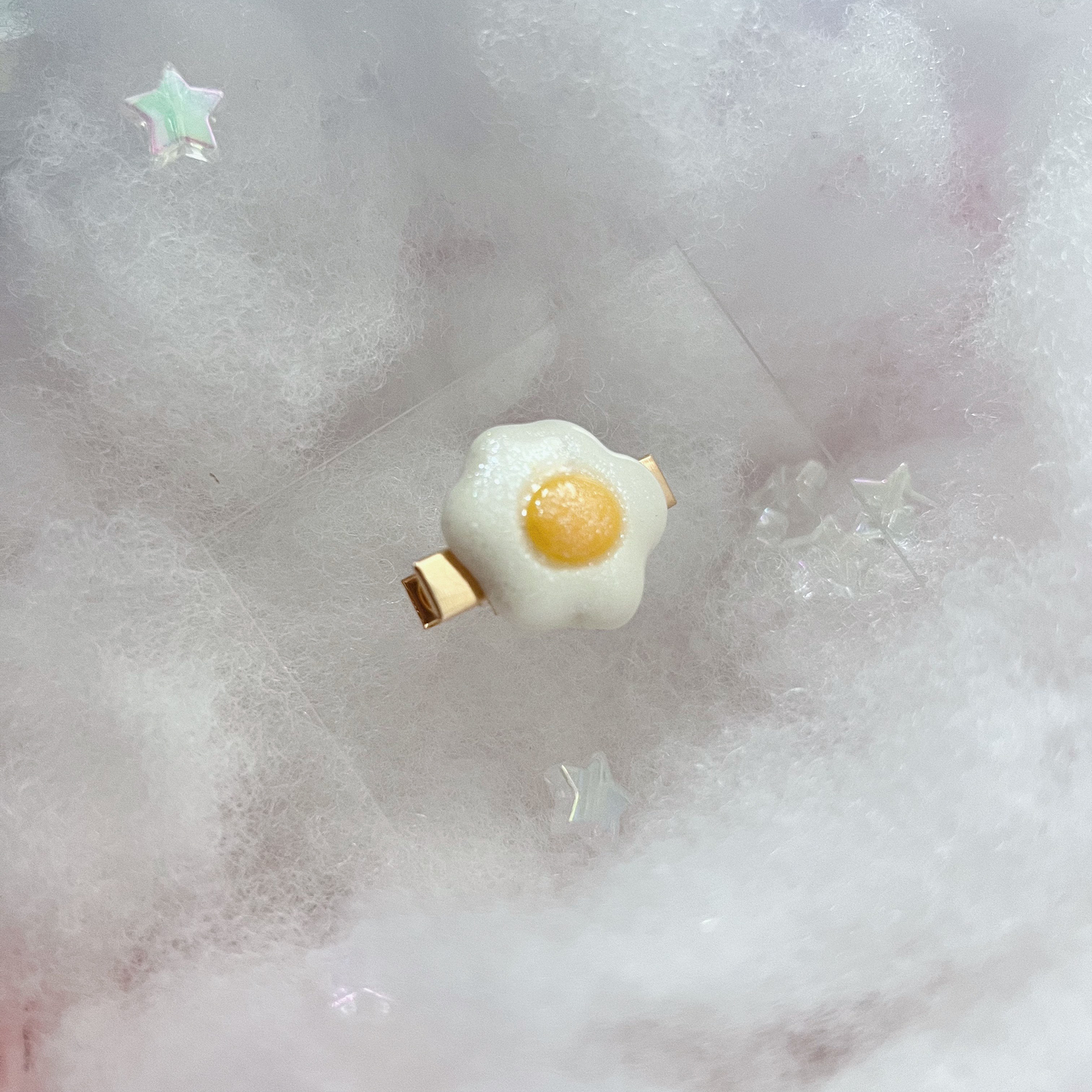 Small eggie hair clip in a dreamy white cloud background.