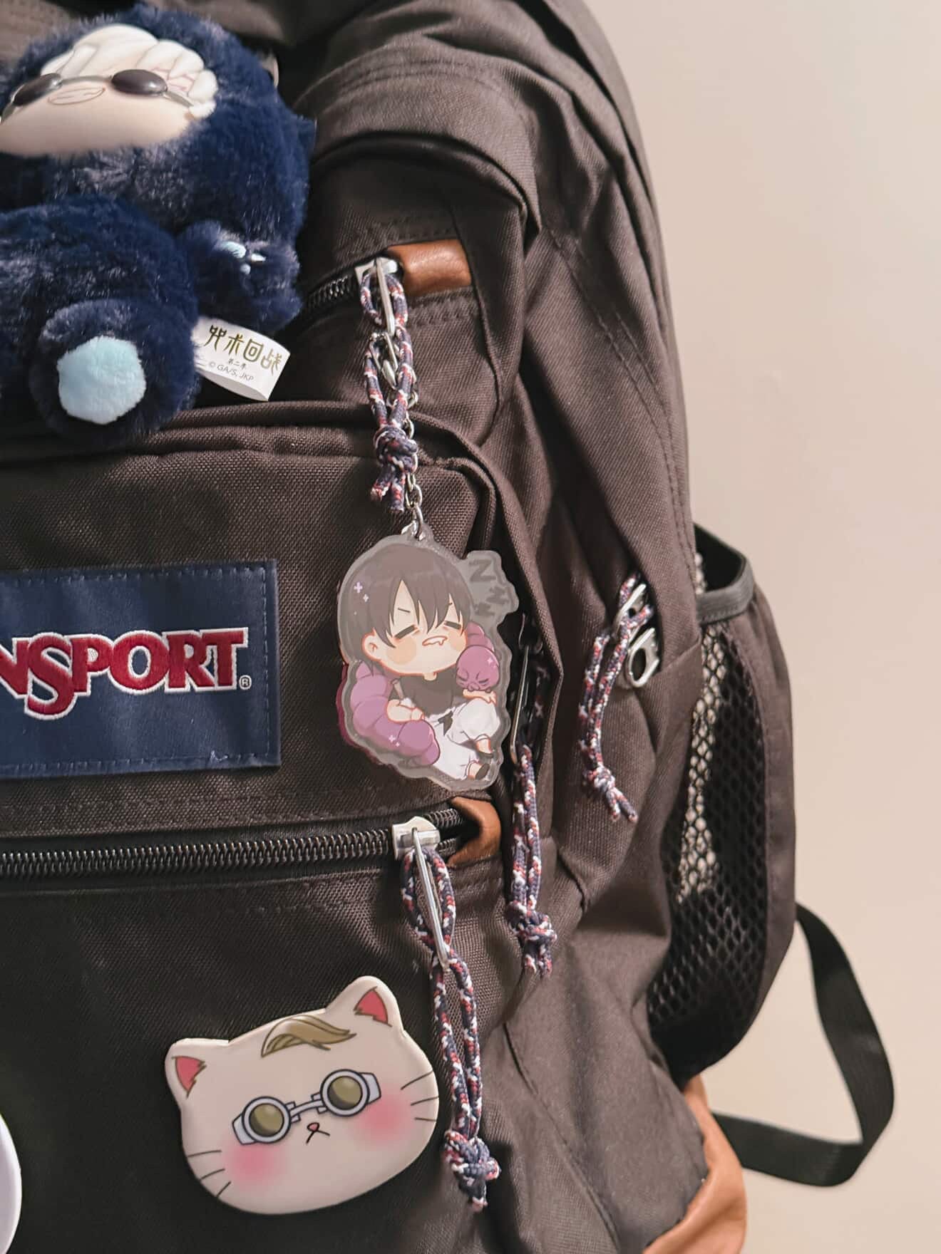 clear acrylic anime keychain featuring sleeping toji fushiguro from jujutsu kaisen with cursed object wrapped around him sleeping displayed on customer's black backpack