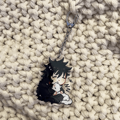 clear acrylic keychain featuring megumi fushiguro from jujutsu kaisen sleeping hugging black and white shikigami puppies