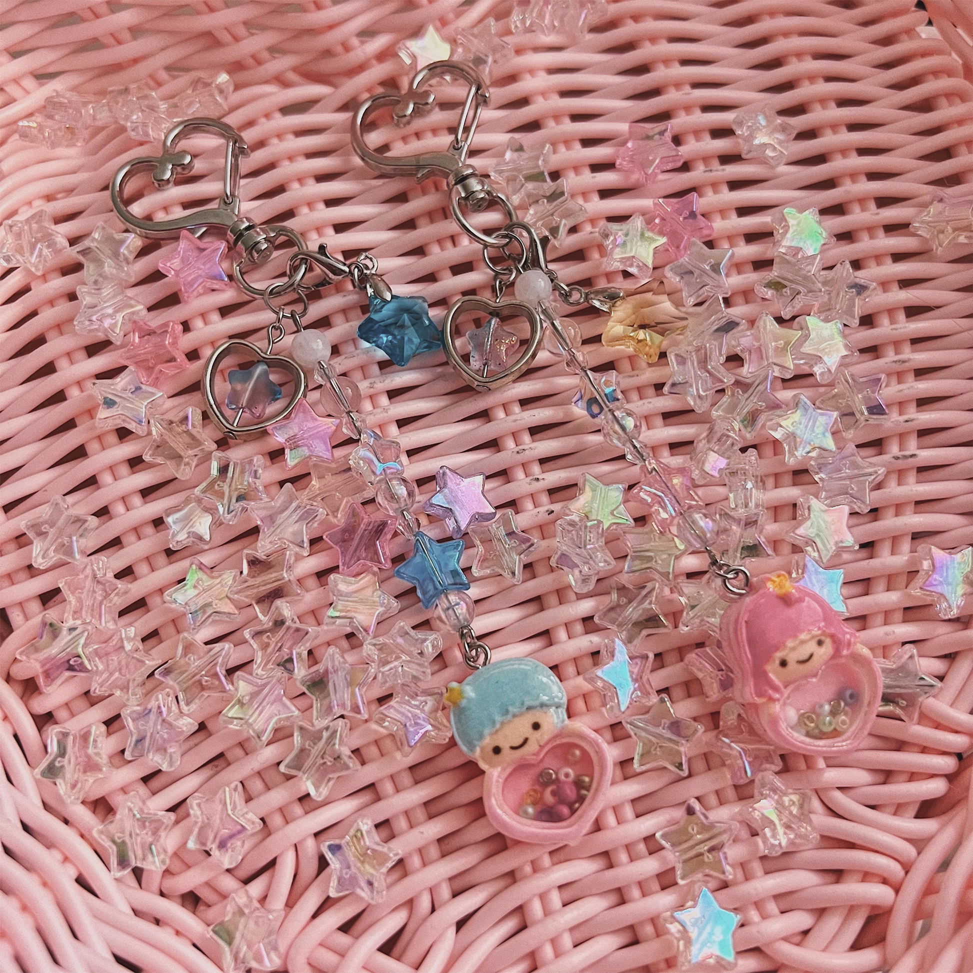 Kiki & Lala, Blue & Pink Twin Star specialty charms with pink weaved basket background with holographic stars.