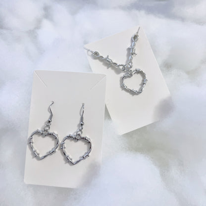 Left is pictured silver metal heart earrings and right features silver heart charm with barbed necklace chain.
