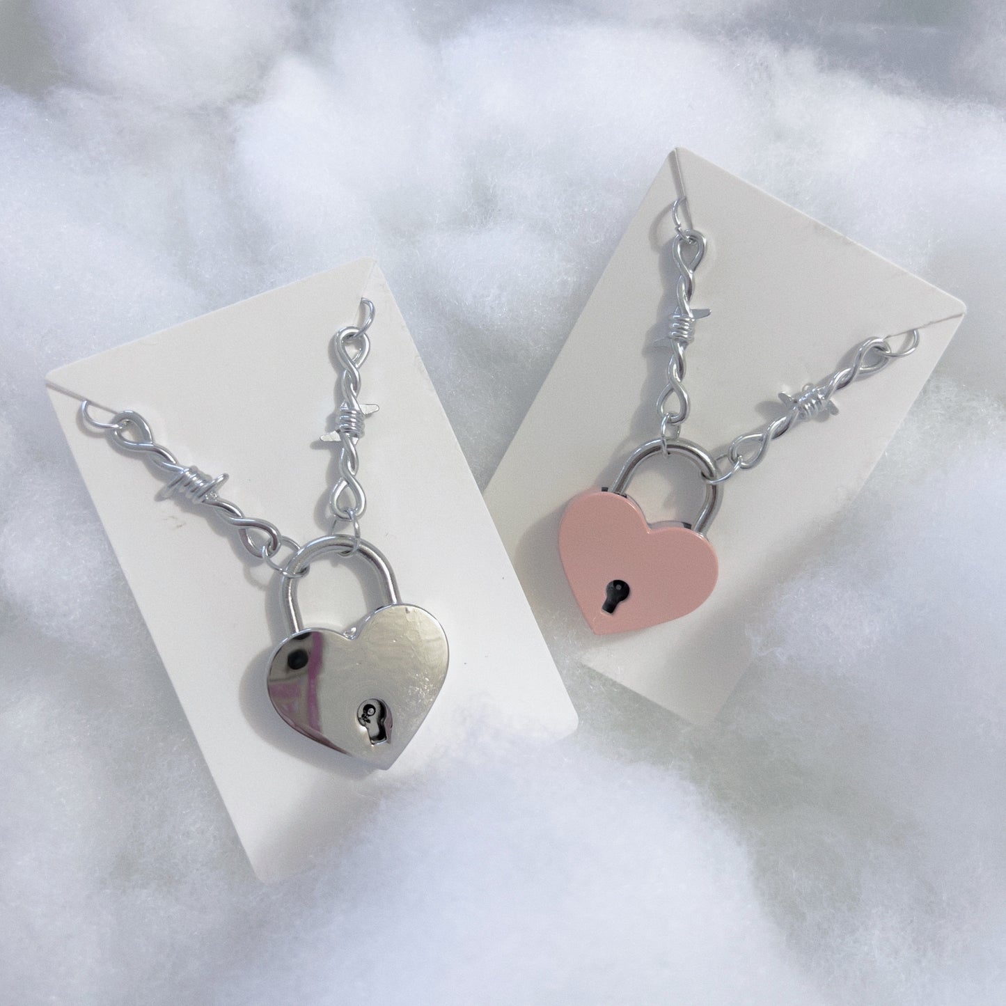 Silver Heart Locket Necklace with barbed necklace chain necklace displayed on the left, pink heart locket with barbed necklace chain necklace on the right.